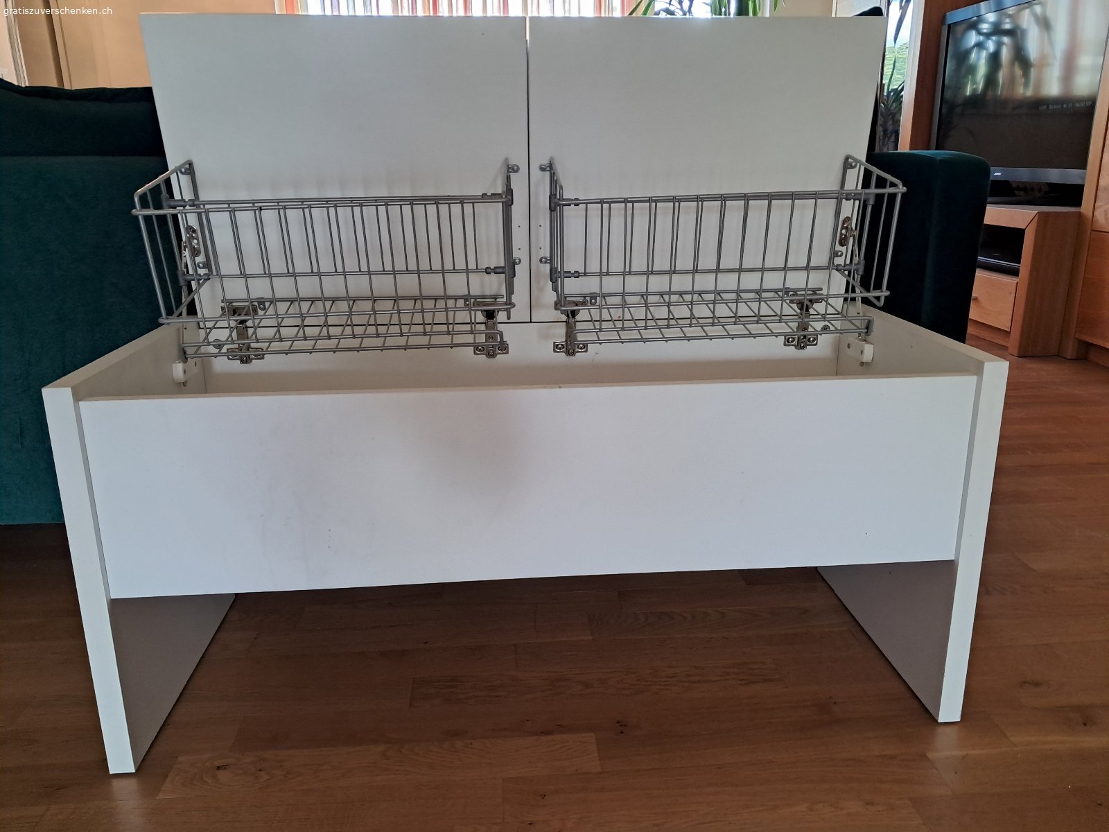 Aufklappbare Garderobensitzbank. Weisse aufklappbare Garderobensitzbank zu verschenken. Länge 1m, Höhe 45.5 cm, Tiefe 41.5 cm. Mit zwei einzeln voneinander zu öffnenden Klappen oben und Gitterhalterungen inwendig. Boden ohne Unterteilung. Muss abgeholt werden.