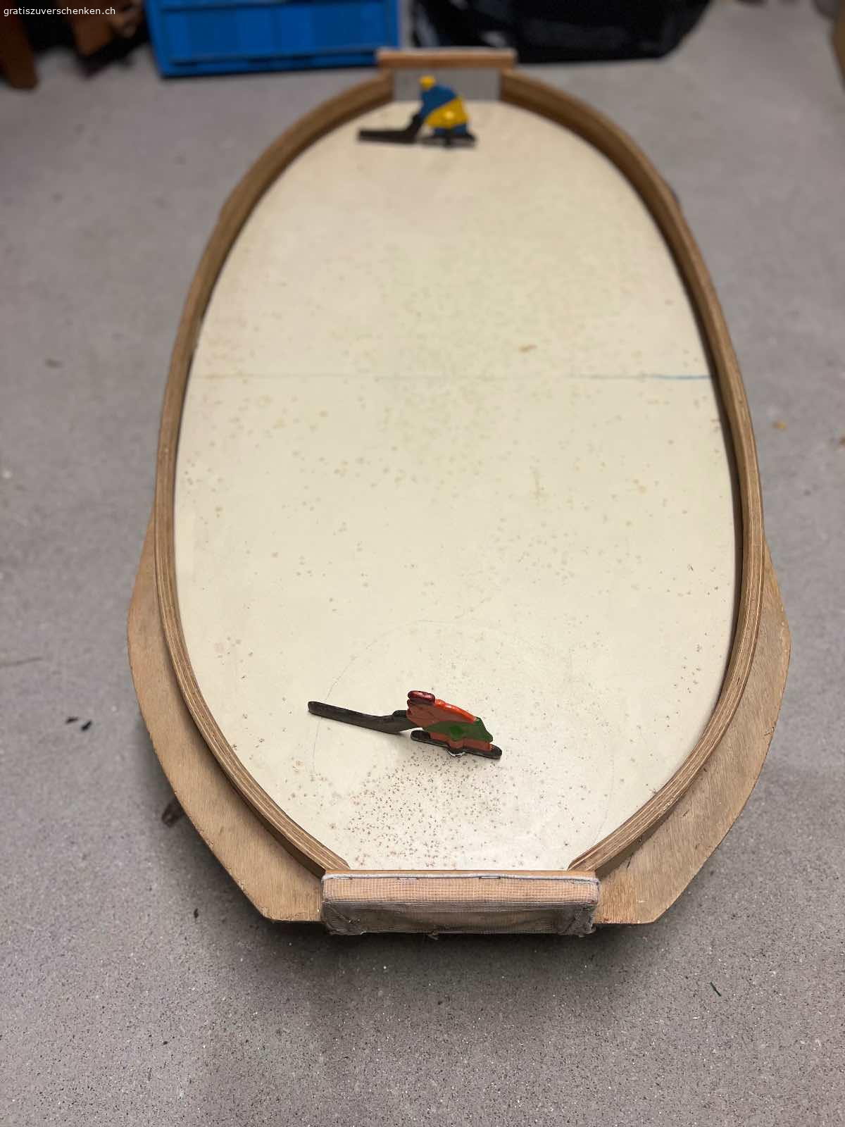 Hockey Spiel aus Holz. Das Spiel wird mit einer Murmel gespielt. Ist das Tor getroffen kommt die Kugel, wie beim Tischfussball auf der Seite raus. Das Spiel ist etwas in die Jahre gekommen, kann jedoch mit etwas Farbe und ein paar Handgriffen ganz einfach aufgehübscht werden.

Wir haben stundenlang damit verbracht - ist wirklich ein schönes und einfaches Spiel und ich würde mich freuen es weiterzugeben.

Grösse 104 cm lang, 52 cm breit und 24 cm tief bzw. hoch.