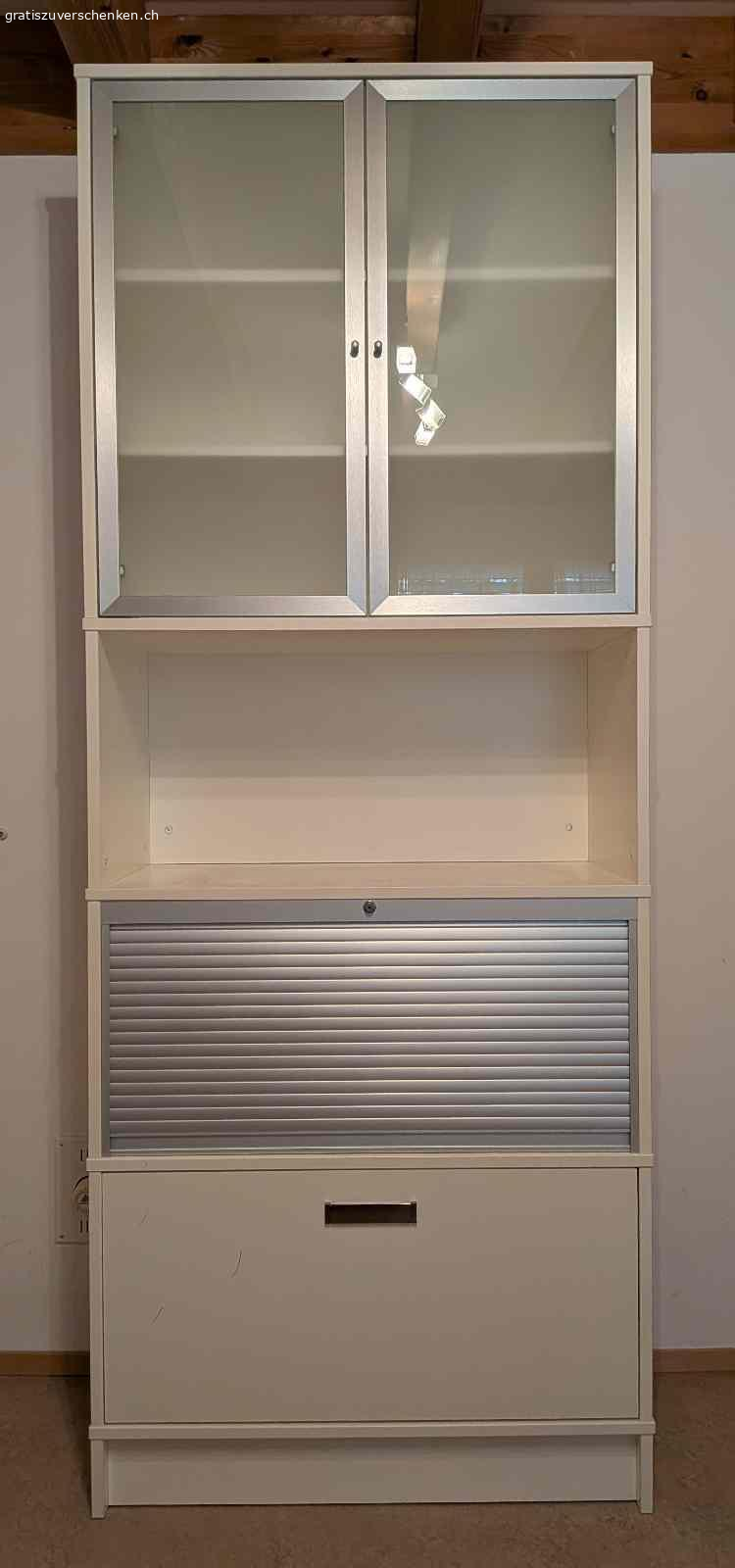 Hübsche schlichte Vitrine für Bücher und Anderes. Hübsches mehrteiliges Gestell mit Schublade und Hängeregistern, Bereich mit Rollade verschliessbar, offener Bereich und Ablage, Bereich mit 2 Glastüren.

Masse: Höhe: 215cm - Breite: 85 cm - Tiefe: 43 cm