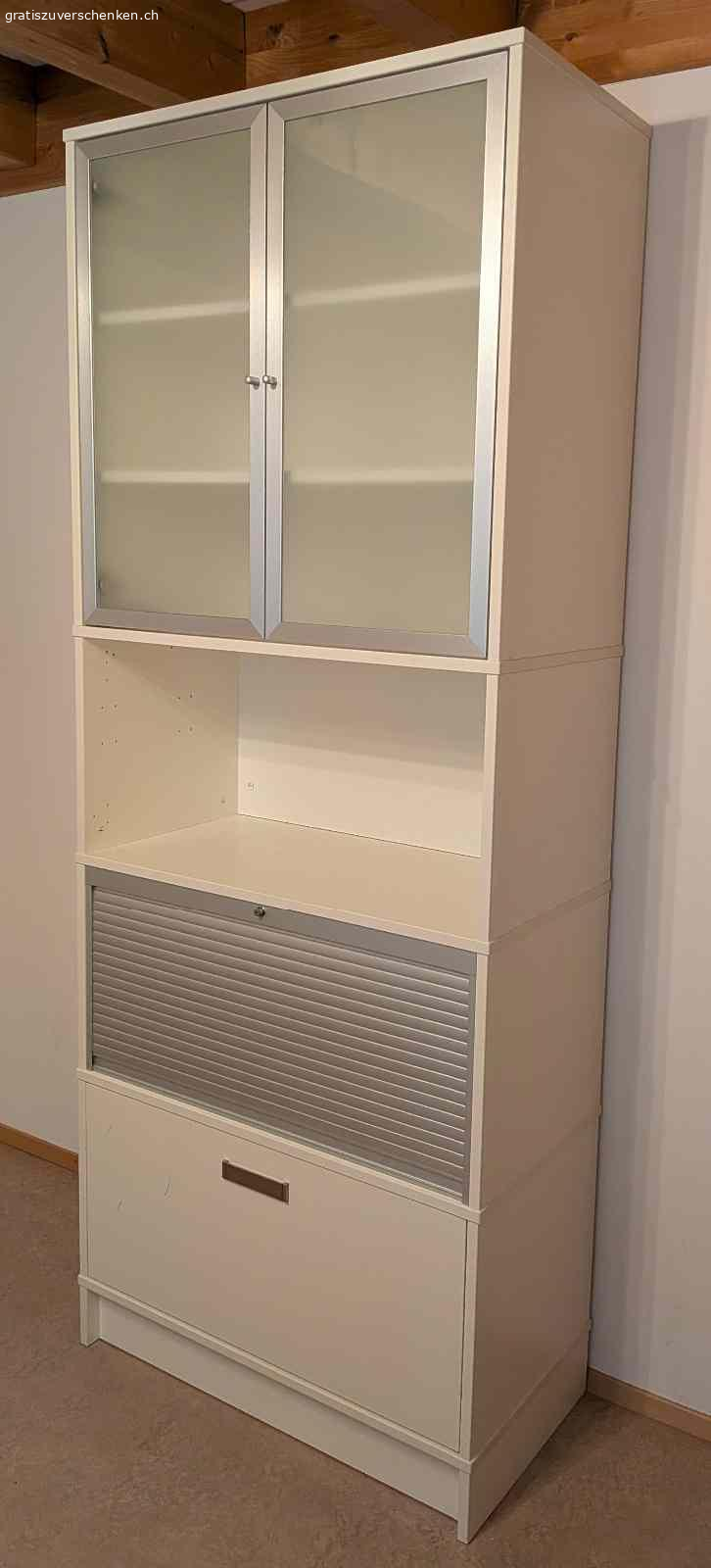 Hübsche schlichte Vitrine für Bücher und Anderes. Hübsches mehrteiliges Gestell mit Schublade und Hängeregistern, Bereich mit Rollade verschliessbar, offener Bereich und Ablage, Bereich mit 2 Glastüren.

Masse: Höhe: 215cm - Breite: 85 cm - Tiefe: 43 cm