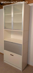 Hübsche schlichte Vitrine für Bücher und Anderes. Hübsches mehrteiliges Gestell mit Schublade und Hängeregistern, Bereich mit Rollade verschliessbar, offener Bereich und Ablage, Bereich mit 2 Glastüren.

Masse: Höhe: 215cm - Breite: 85 cm - Tiefe: 43 cm